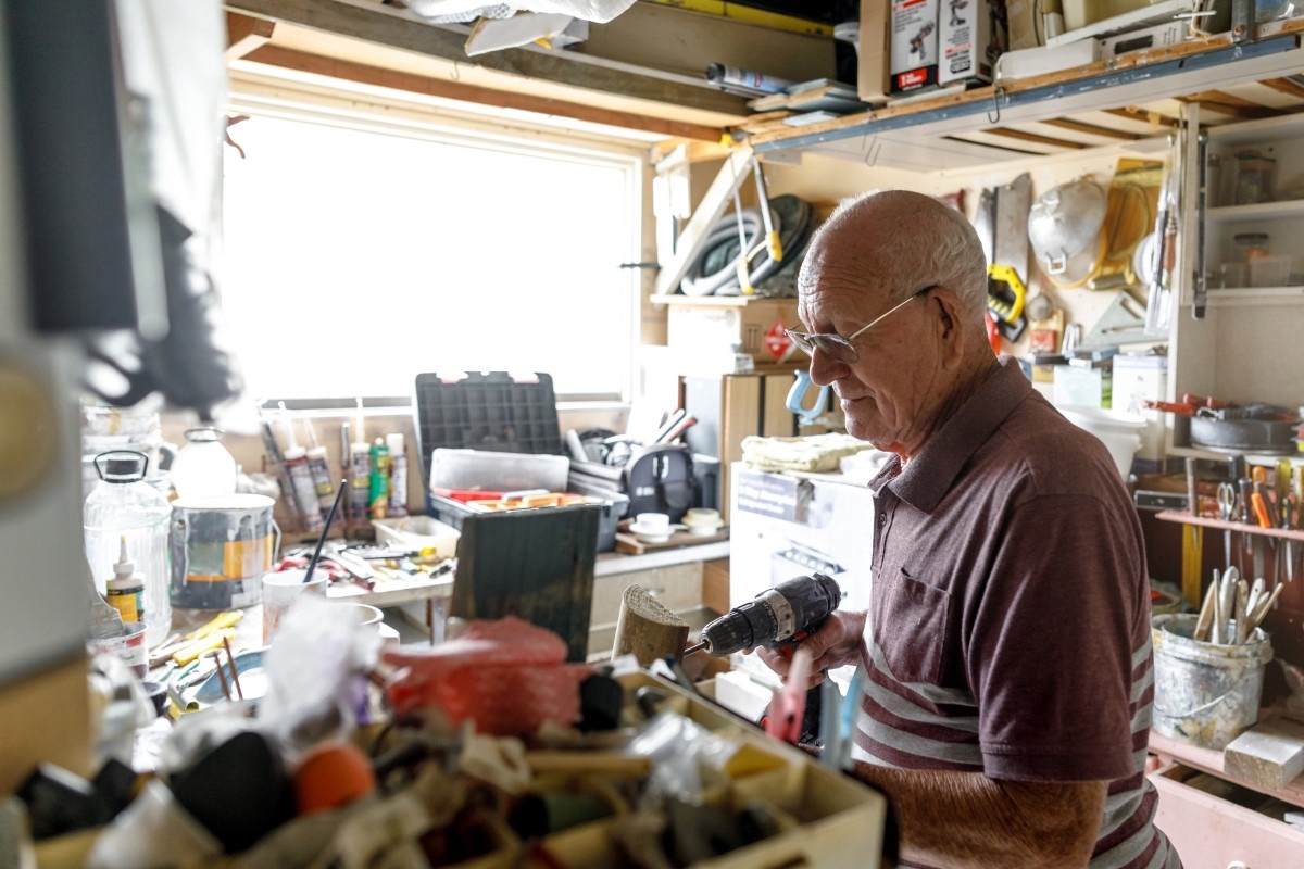 older man working with tools in shed