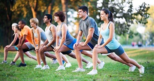 Fitness group stretching outdoors in a park