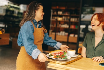 a woman serving a sandwich at a cafe
