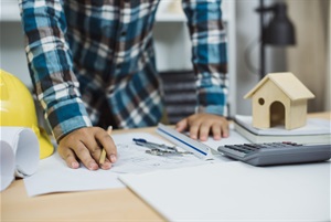 Man leaning over property plans on desk